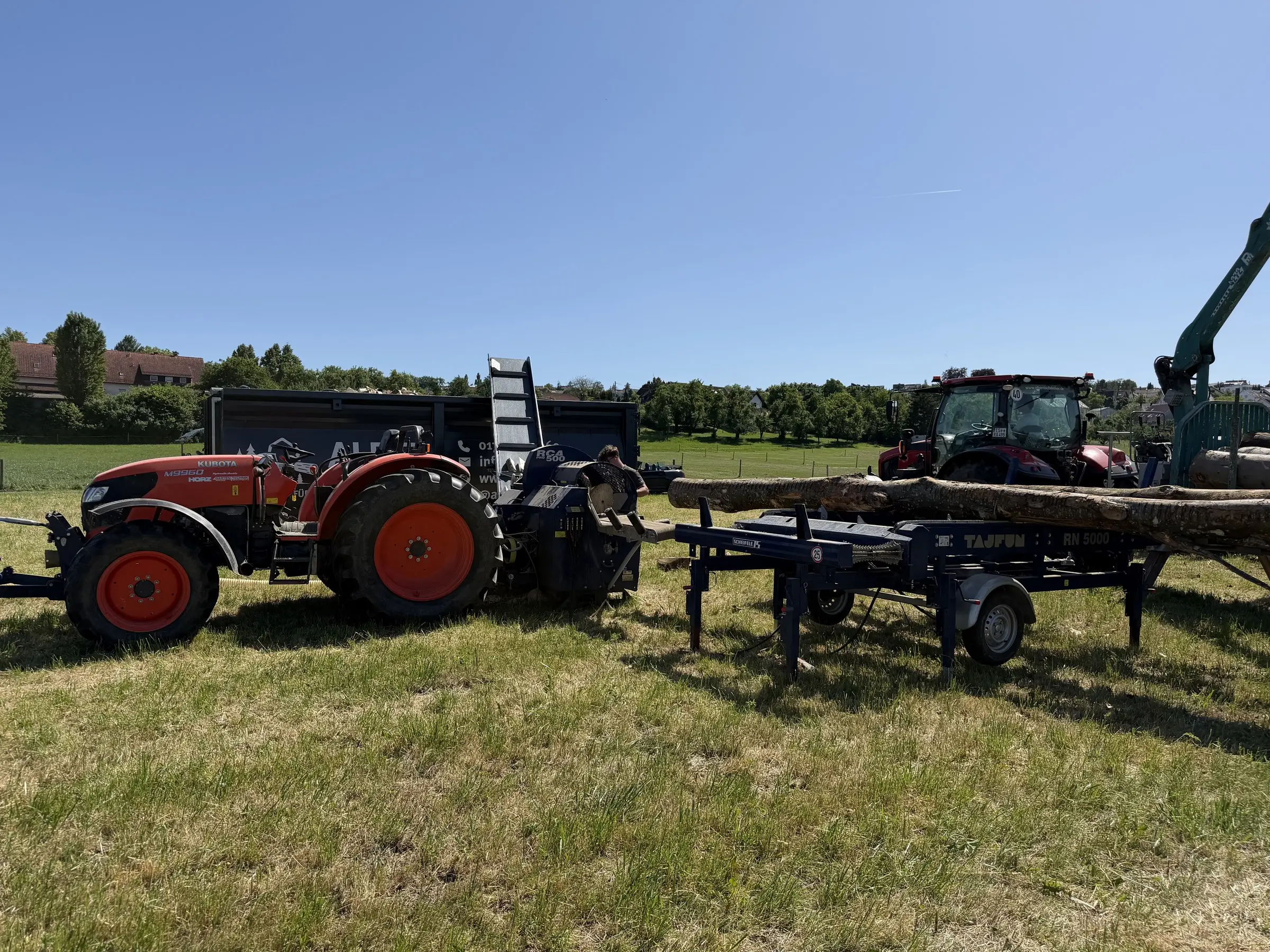 Traktor mit Sägespaltautomat und Rückewagen auf der Wiese